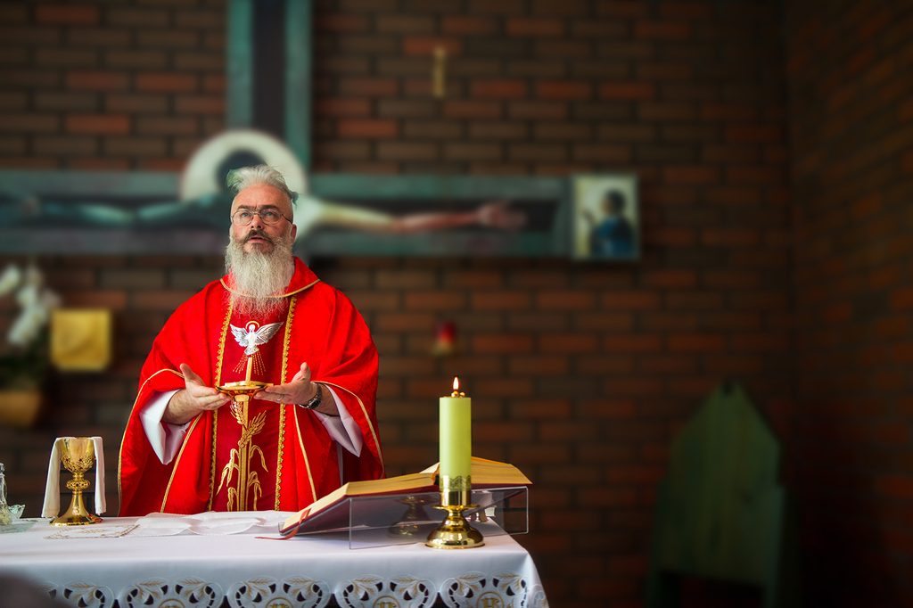 Kapłan w czerwonym ornacie sprawujący Mszę Świętą przy ołtarzu